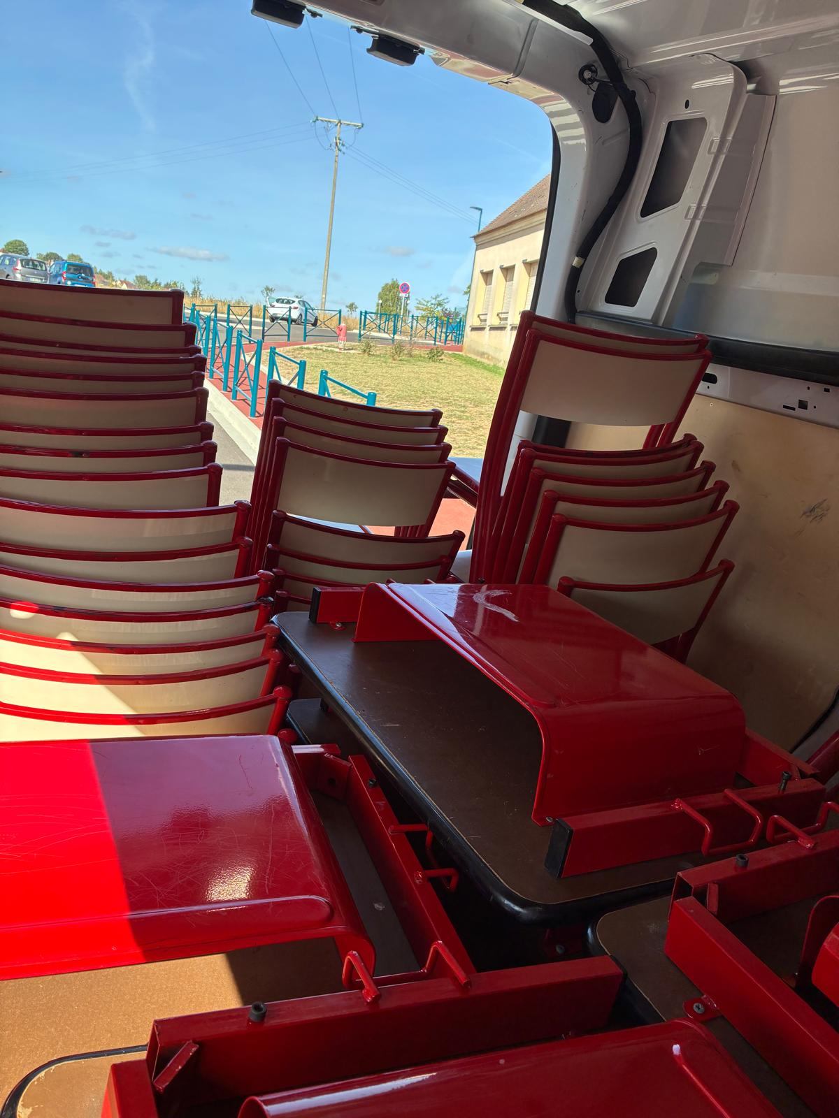Vue de l'intérieur de la camionnette chargée, portes ouvertes sur la rue