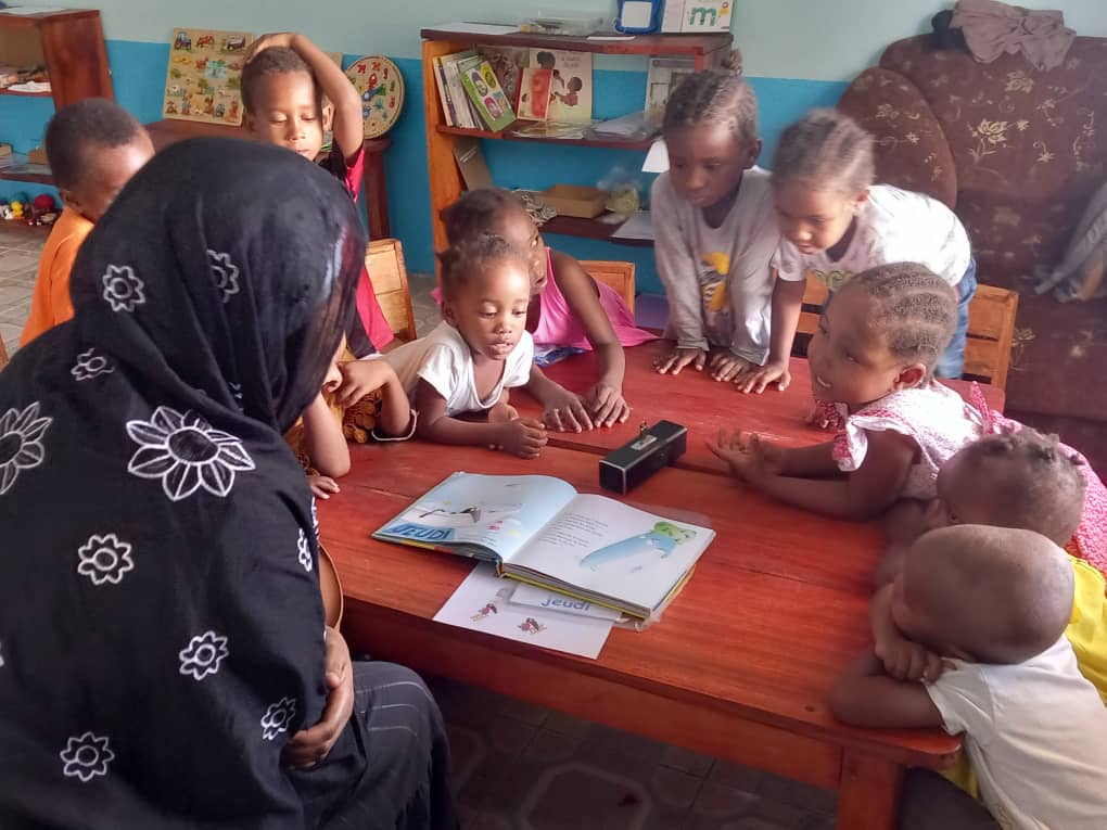 Une enseignante fait la lecture à un groupe d'enfants à la Maison des Enfants Lumières