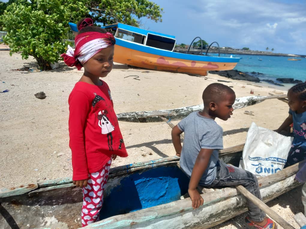 Des enfants explorent une pirogue traditionnelle échouée sur une plage de Grande Comore