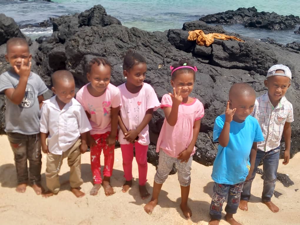 Des enfants posent sur les roches volcaniques noires d'une plage comorienne
